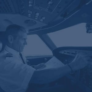 Male pilot in aircraft cockpit with navy-toned filter.